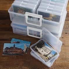 several plastic storage containers with pictures and cards inside on a wooden table next to a pair of scissors