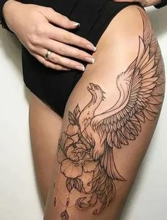 a woman's thigh with an eagle and flowers tattoo on the side of her leg