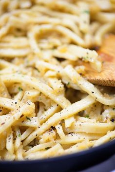 a pan filled with pasta and a wooden spoon