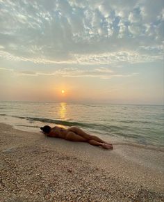 a woman laying on the beach at sunset