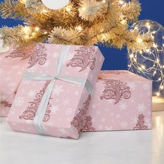 three wrapped presents under a christmas tree with lights and decorations on the branches in front of it