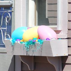 some balloons and streamers are sitting in a window sill on the front porch