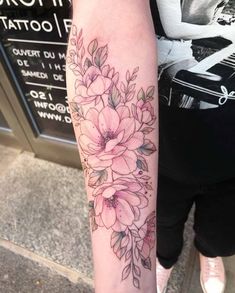 a woman's arm with flowers on it and the words tattoo written in black ink