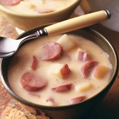 two bowls filled with soup on top of a wooden table next to crackers and bread