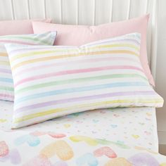 two pillows on top of a bed with pink and green striped pillow cases next to each other