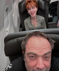 a man sitting in an airplane looking at the camera