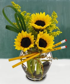 a vase filled with yellow flowers and pencils