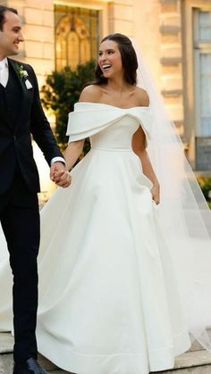 a bride and groom holding hands while walking down the steps in front of a building