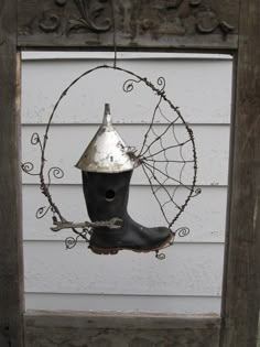 a bird feeder hanging from the side of a white house with an old window frame