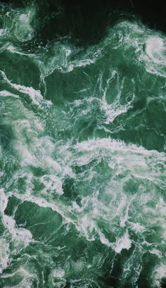 the water is green and white as it looks like foamy waves are coming up from the ocean