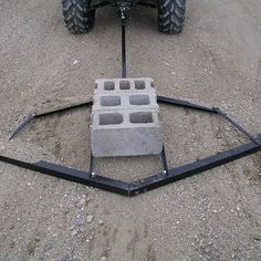 a cement block sitting in the middle of a dirt field next to a tractor tire