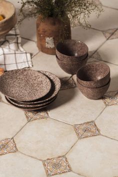 a table topped with plates and bowls on top of a tiled floor