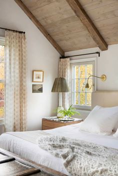 a white bed sitting under a wooden ceiling