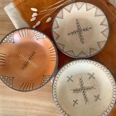 three brown and white plates sitting on top of a wooden table next to an orange pillow