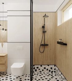 a modern bathroom with black and white tiles on the floor, shower head, and toilet