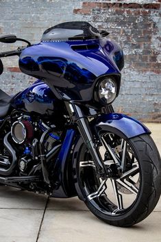 a blue motorcycle parked in front of a brick wall