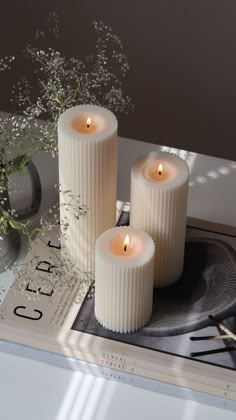 three white candles sitting on top of a tray