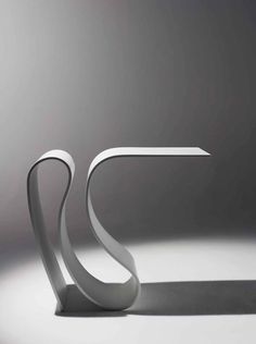 a white table sitting on top of a floor next to a gray wall with an abstract design