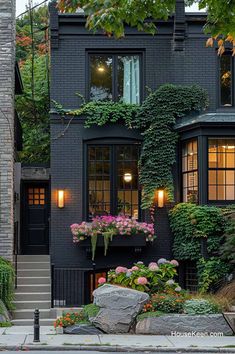 a black house with lots of windows and plants on the outside wall, along with steps leading up to it