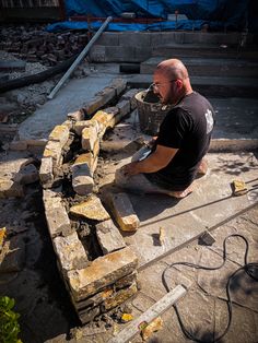 a man sitting on top of a pile of bricks next to a building under construction