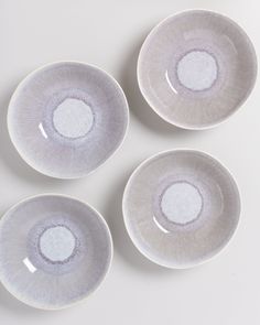 four white bowls with silver rims on a table