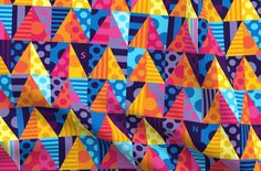 brightly colored party hats are hanging on the side of a colorful wall with polka dots and circles