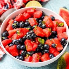 watermelon and blueberry salad in a white bowl with limes on the side