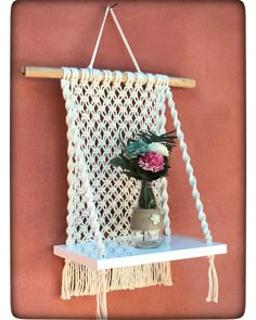 a macrame hanging on the wall with flowers in a vase next to it