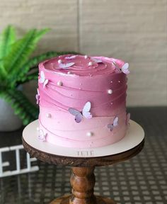 a pink and white cake sitting on top of a wooden stand