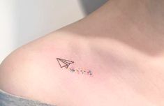 a woman's shoulder with a small airplane tattoo on the left side of her chest