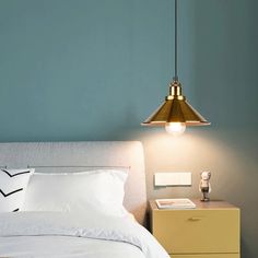 a bed with white sheets and pillows under a hanging light over the headboard in a bedroom