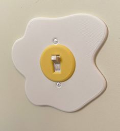 a yellow and white light switch sitting on top of a wall