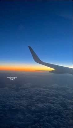 the wing of an airplane as it flies above the clouds at sunset or dawn in the sky