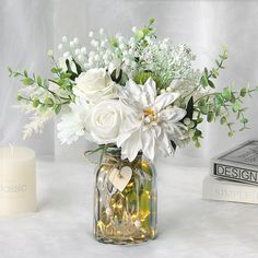 a vase filled with white flowers next to a candle