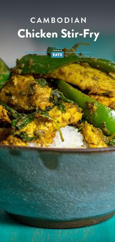 chicken stir - fry in a blue bowl with rice and green peppers on the side