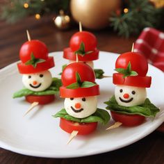 small tomatoes with faces made to look like people wearing tomato hats and green leaves on them