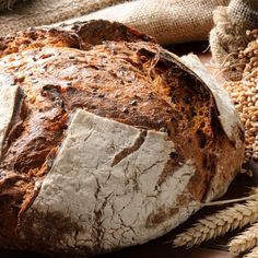 a loaf of bread sitting on top of a wooden table next to some wheat and burl