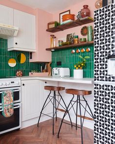 a kitchen with green tiles and wooden stools in front of the stove top oven