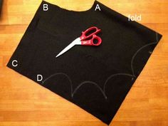 a pair of scissors sitting on top of a black piece of cloth next to a ruler