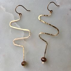 The Squiggle Earrings feature a colorful bead of your choice on a gold-filled squiggly dangle that is hammered to give it texture and secured to an elegant handmade gold-filled ear wire. Color options shown with a sterling silver squiggle are just to show the bead; every earring under this listing will be gold fill. To view sterling silver options, click here. These earrings are mindfully made with high-quality gold-filled metals. They are made with handmade gold-filled ear wires as well. They a Wire Wrapped Shell Jewelry, Squiggle Earrings, Metal Earrings Handmade, Gold Wire Ring, Wire Earrings Handmade, Earrings Diy Handmade, Diy Beaded Rings, Earring Inspo, Fancy Earrings