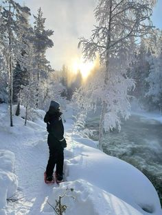 a person standing in the snow on skis looking out over a river and trees