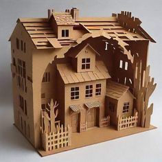 a paper model of a house with trees on the roof and fenced in yard