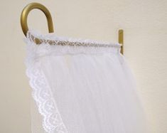 a white curtain hanging on a brass hook