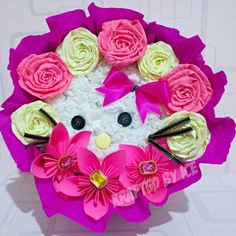 a pink and white kitty with flowers on it's head is shown in the shape of a bouquet