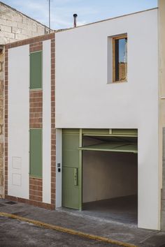 an empty parking garage in front of a brick building with green shutters on the doors