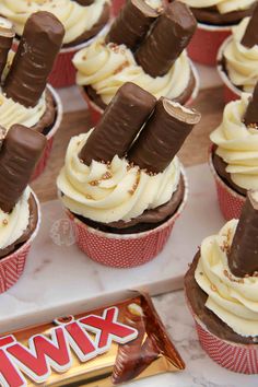 chocolate cupcakes with white frosting and candy sticks sticking out of the top