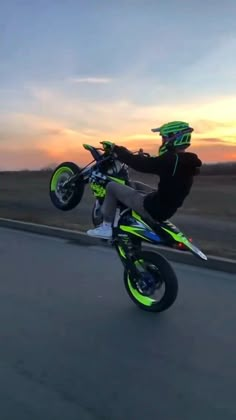 a person on a motor bike doing a trick in the air at sunset or dawn