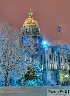 the capitol building is lit up in blue and white for christmas time with snow on the ground