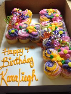 a box filled with lots of cupcakes on top of a white sheet cake