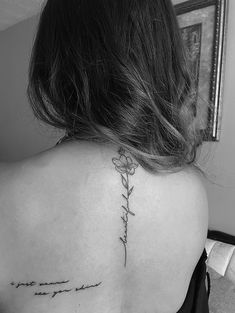 the back of a woman's shoulder with an inscription tattoo